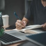 man hands with pen writing notebook officelearning education workwrites goals plans make wish list desk